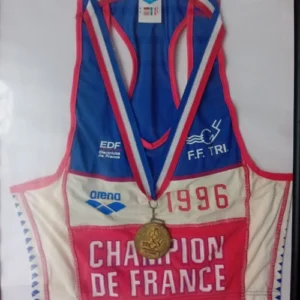 Combinaison officielle de triathlon "Champion de France 1996" de la F.F.TRI, avec une médaille dorée, marquant un moment fort dans le parcours sportif de l’athlète.