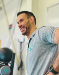 Thomas Cuisset, éducateur sportif, souriant et détendu dans une salle de sport, symbolisant son engagement dans le sport-santé.