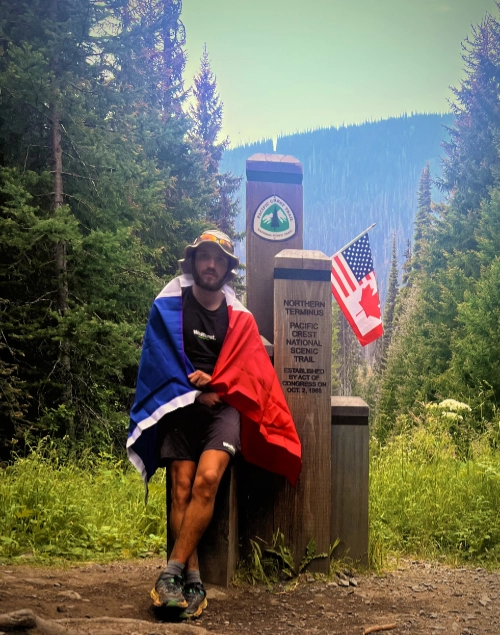 Antoine Clément termine son défi d’ultra-endurance sur le Pacific Crest Trail, posant au terminus nord avec un drapeau français.