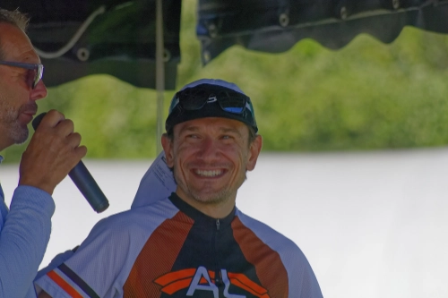 Un participant souriant portant un maillot de course est interviewé sur scène lors d’une course nature à Le Croisic.