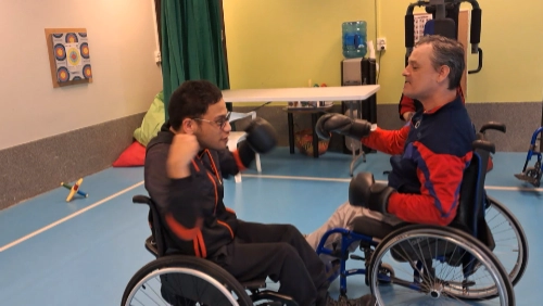 Deux hommes en fauteuil roulant s’entraînent à la boxe dans une salle de sport au Croisic, illustrant concrètement l’inclusion handicap sport Le Croisic par la pratique d’un sport adapté.