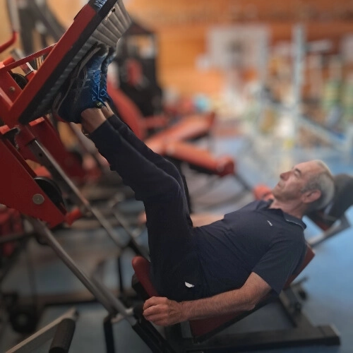 Senior effectuant un exercice de musculation des jambes en salle au Croisic, dans le cadre d’une retraite active et sportive.