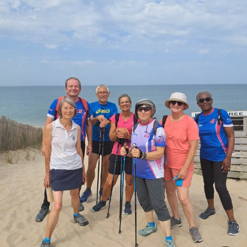 Groupe de seniors en marche nordique sur la plage à La Turballe, illustrant une retraite active et sportive.