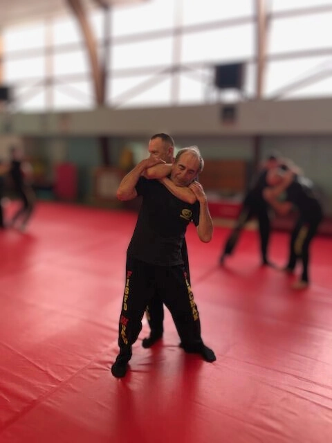 Seniors en pleine démonstration de self-défense lors d’un atelier en salle au Croisic, illustrant une retraite active et sportive.
