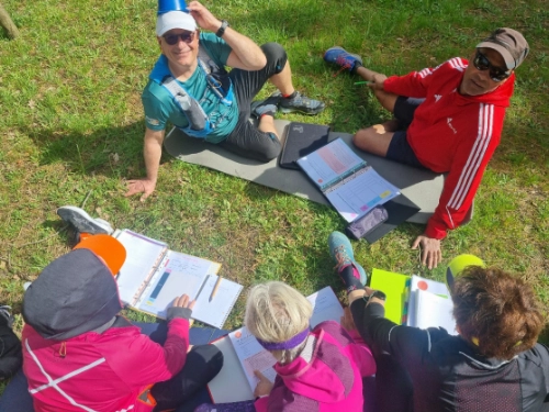 Groupe de participants assis en cercle en extérieur, en pleine session théorique sur la marche nordique technique et pédagogie, avec supports pédagogiques.
