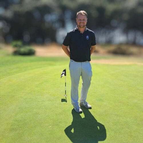 Homme souriant debout sur un green de golf au Croisic, représentant le développement local de ce sport.