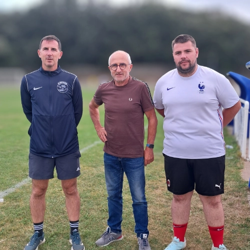 rois membres du staff du club de football Le Croisic posant debout sur le bord du terrain.