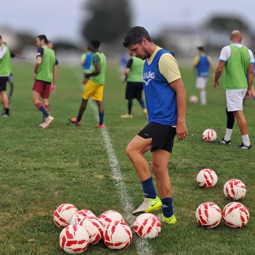 Joueur du club de football Le Croisic en pleine préparation avec des ballons sur le terrain avant l'entraînement.