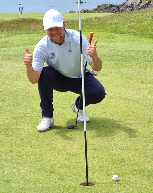 Golfeur souriant accroupi près d’un trou sur le green au Croisic, illustrant l’enthousiasme autour du développement du golf local.
