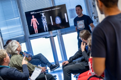Présentation sur l’IRM musculaire devant un groupe de personnes, illustrant la sensibilisation à la santé du muscle dans un contexte de santé publique.
