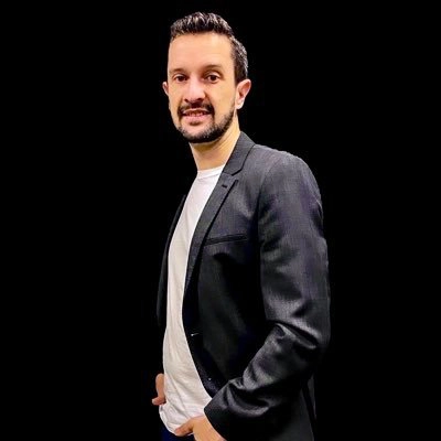Portrait d’un homme en veste sombre sur fond noir, incarnant une réflexion contemporaine sur l’héritage Paris 2024.