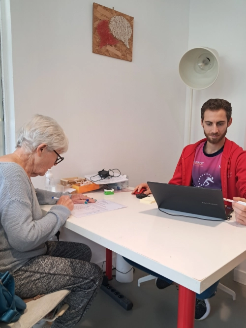 Séance de suivi ou d’évaluation dans le cadre d’une activité de sport santé à Saint-Nazaire, avec une personne senior travaillant sur une feuille face à un professionnel utilisant un ordinateur.