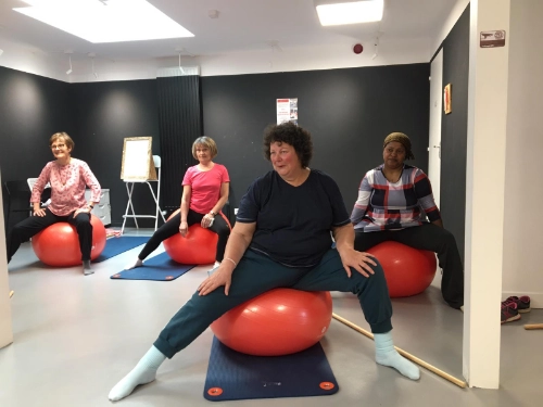 Groupe de personnes participant à une séance de sport santé à Saint-Nazaire, assises sur des gros ballons de gymnastique dans une salle.