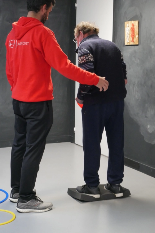 Exercice d’équilibre encadré dans le cadre d’une séance de sport santé à Saint-Nazaire, avec une personne debout sur un plateau de proprioception accompagnée par un intervenant.