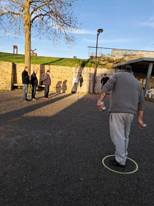Partie d’entraînement du club de pétanque du Croisic avec un joueur au tir et des membres observant la scène.