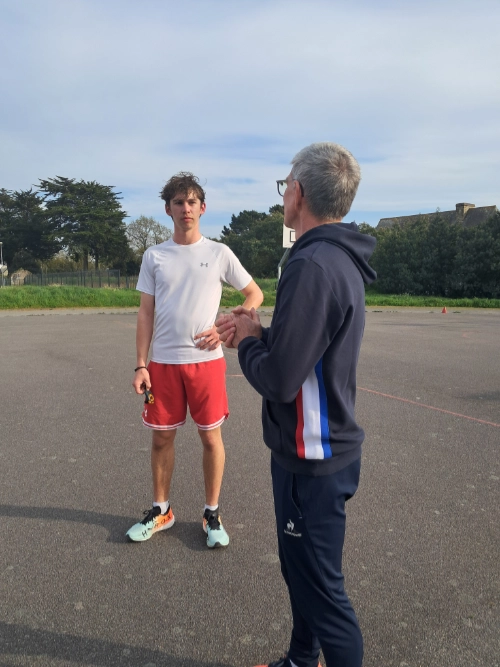 Un enseignant échange avec un élève en tenue de sport sur un terrain extérieur lors d’une séance d’EPS au lycée La Mennais de Guérande.