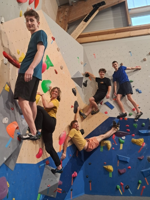 Groupe de jeunes grimpeurs posant sur un mur d’escalade de bloc en salle dans un club d’escalade à Batz-sur-Mer.