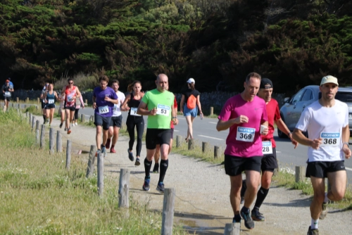 Coureurs de la Course Nature du Croisic 2026 sur un chemin côtier, avec la route et la végétation en arrière-plan.