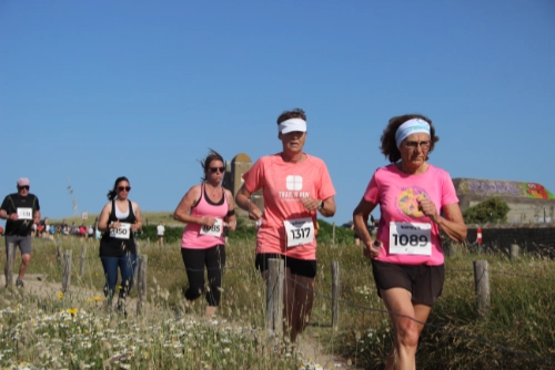 Coureurs participant à la Course Nature du Croisic 2026 sur un sentier côtier bordé de fleurs sauvages.