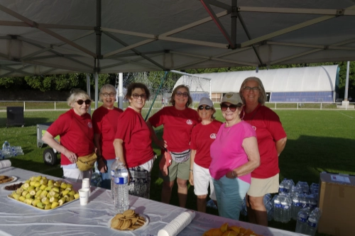 Bénévoles de la Course Nature du Croisic 2026 sous un stand de ravitaillement avec boissons, fruits et biscuits.
