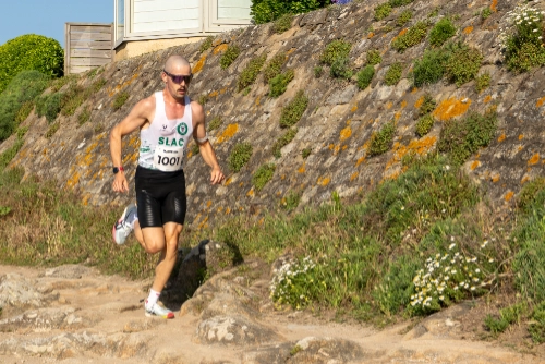 Coureur de la Course Nature du Croisic 2026 montant des marches en pierre le long d’un muret végétalisé.