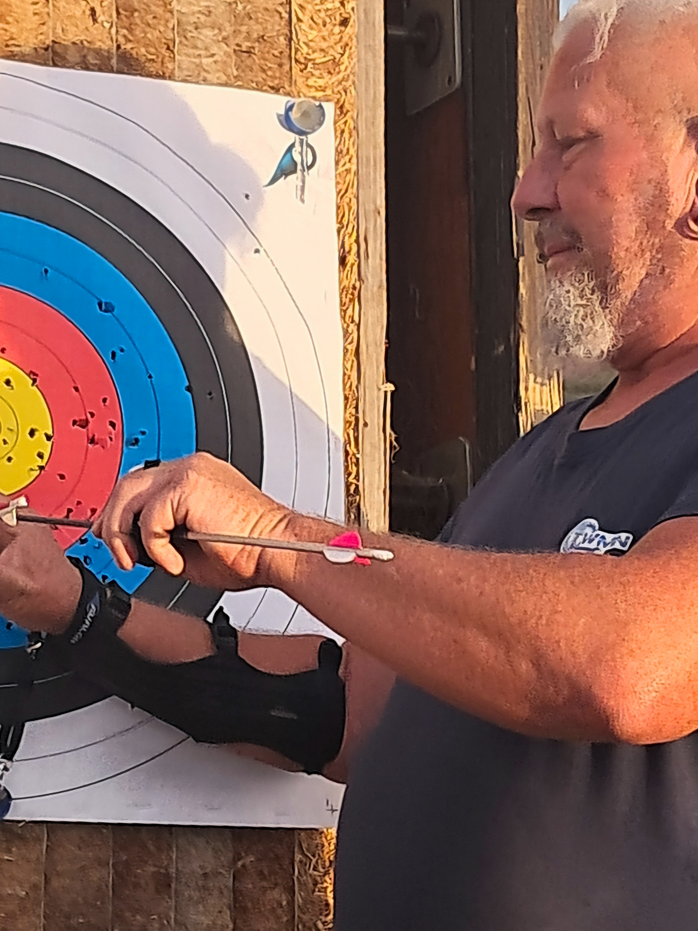 Un archer examine ses flèches près d’une cible de tir à l’arc